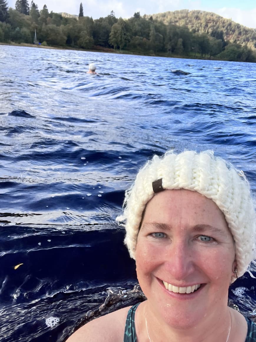 Rebecca wearing a woolly hat by a lake