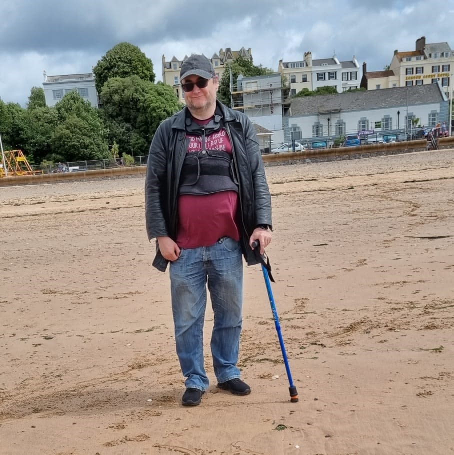 Glen on the beach with a walking stick